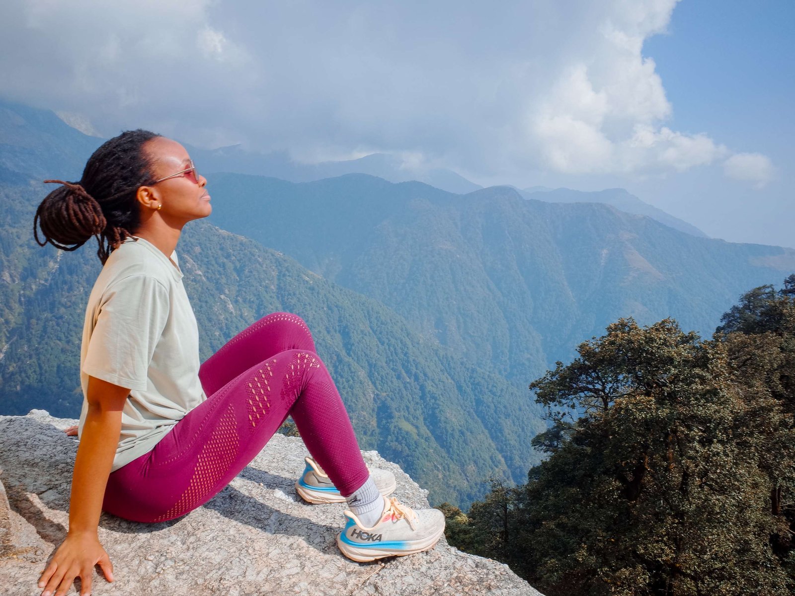 Black woman in hiking attire at the top of Triund Trek in the Himalayas, India