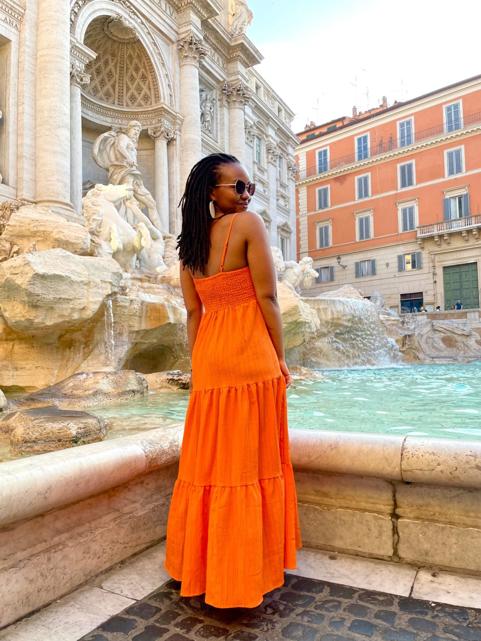 Woman in orange dress posing in by Trevi Fountain in Rome