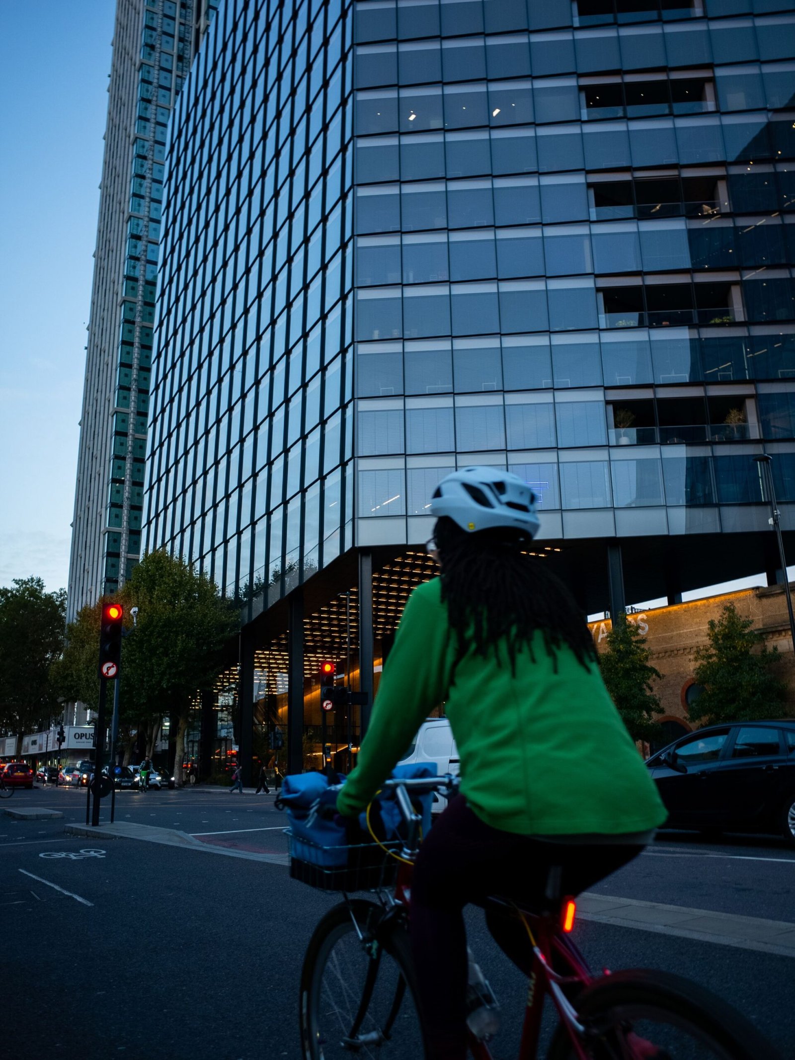 Person in green cycling with a view of london skyscrapers