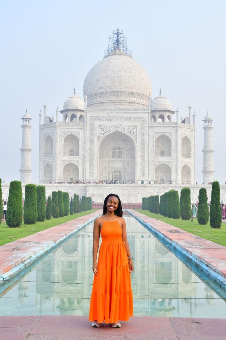 Black woman in orange dress in front of the Taj Mahal, India