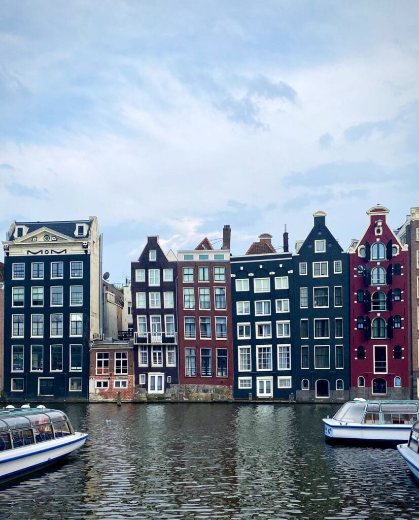 Row of colorful buildings overlooking the water and boats in Amsterdam, Netherlands