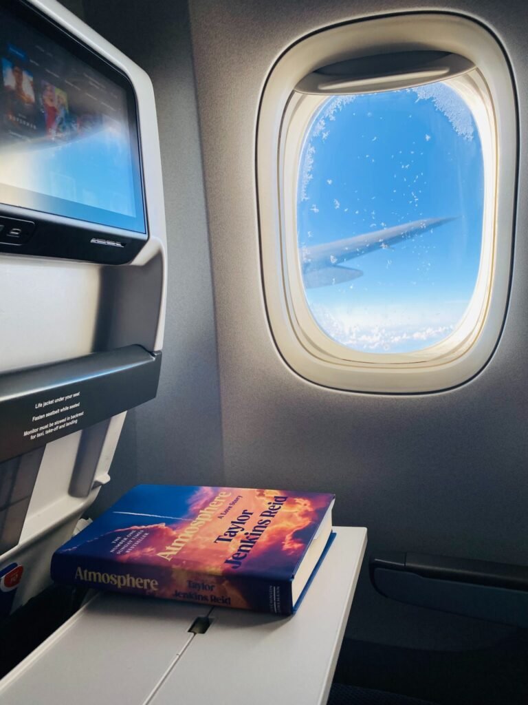 Taylor Jenkins Reid book on airplane table tray with the wing visible through the window