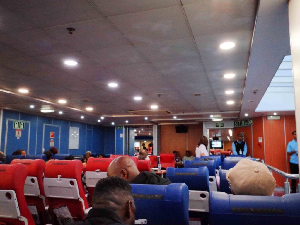 passengers seated in blue and white chairs inside the trinidad and tobago ferry