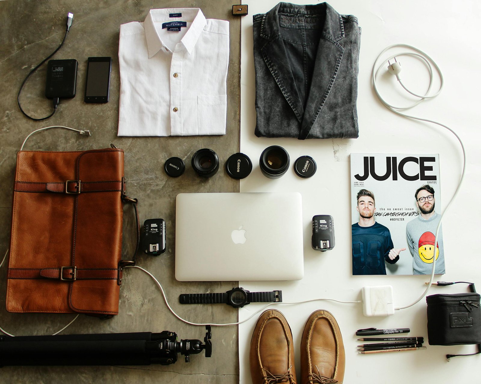 Neatly arranged travel essentials including clothing, tech gear, and a magazine.