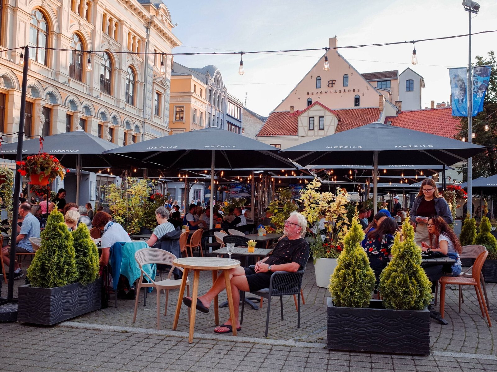 People sitting at a cozy restaurant terrace in Riga city centre, Latvia on a bright summer day