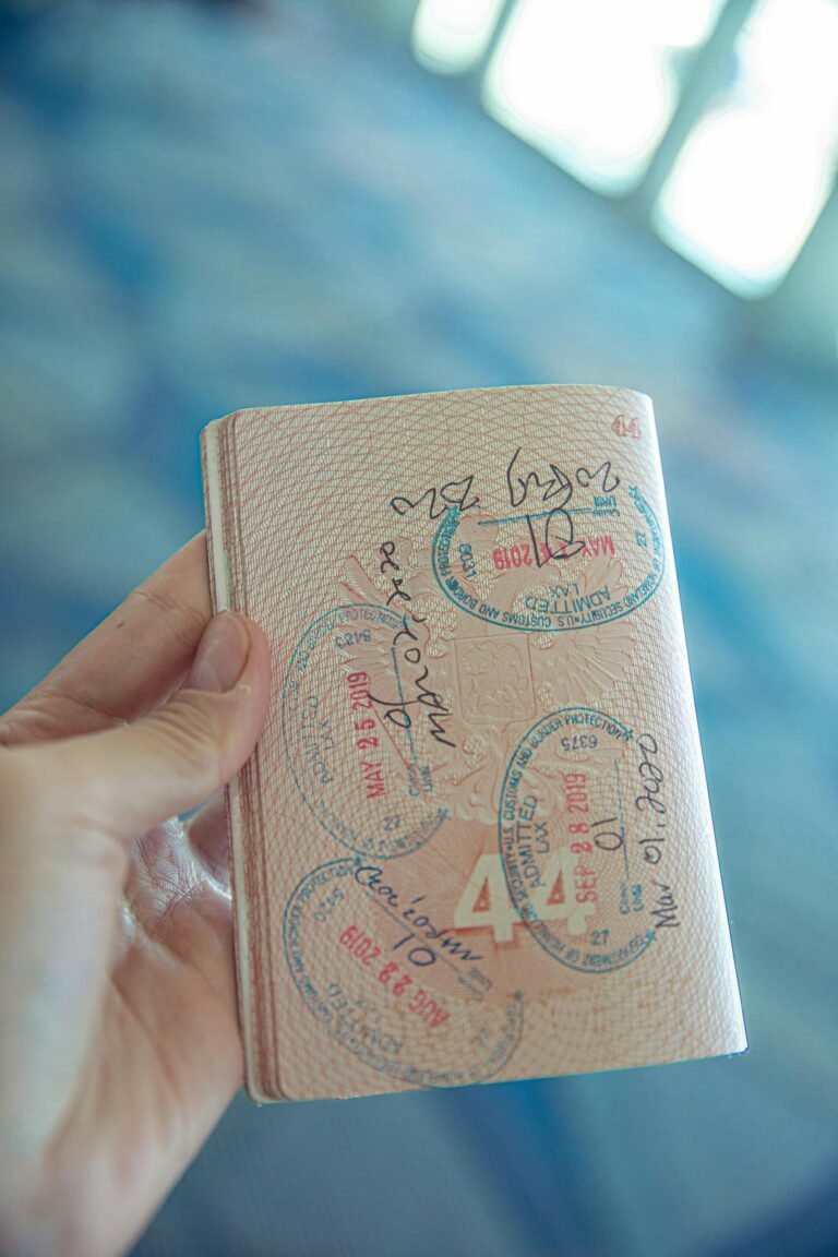 A close-up view of a hand holding an open passport with various stamps, highlighting travel experiences for visa applications.