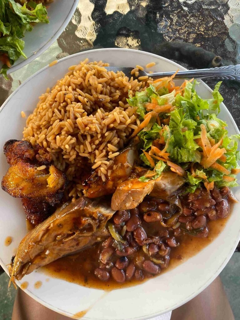 example of caribbean food consisting of rice and peas, plantain, salad and fresh fish