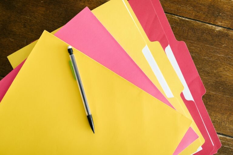 Colorful folders and pen arranged on a wooden table in preparation for visa application