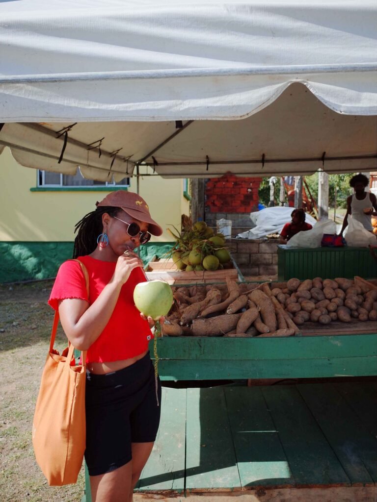 woman drinking fresh coconut water infront a fruit stall in the Caribbean