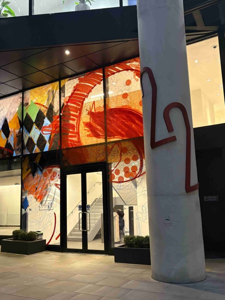 Entrance to Horizon 22 at 22 Bishopsgate, featuring colourful artwork across glass panels and the building’s lobby doors.
