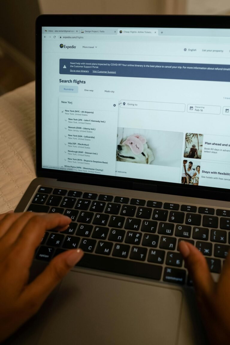 Person typing on laptop, searching flight details indoors, focusing on preparing booking confrimation for visa application