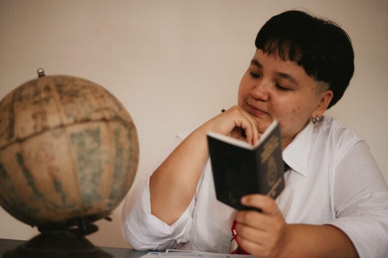 A pensive young adult reading a passport next to a vintage globe, symbolizing visa struggles and travel dreams